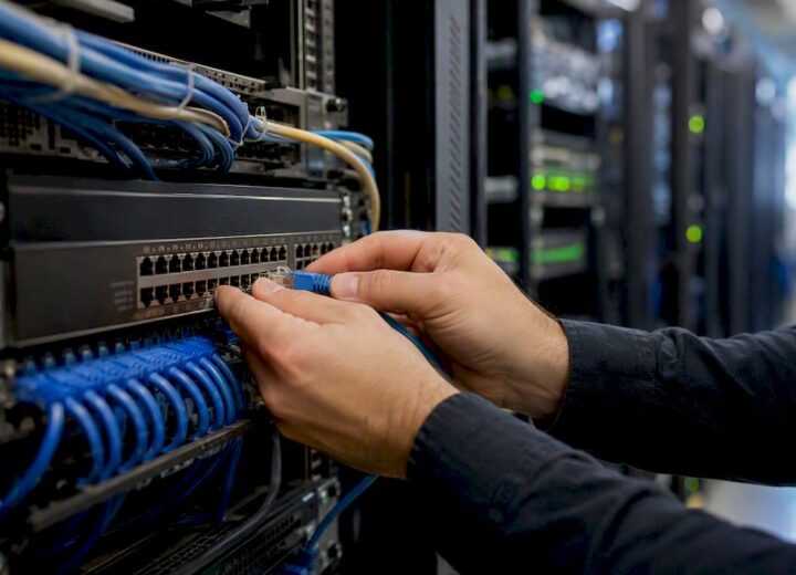 SaaS monitoring for UK IT teams: performance and reliability - Re-solution Hands connecting Ethernet cable to network switch